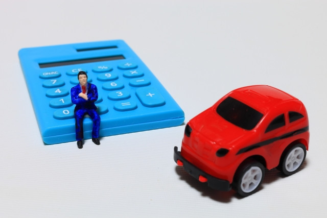 電卓の上にいる大人の男性の人形とおもちゃの車