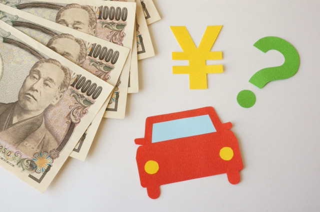 数枚の一万円札とフェルト生地でできた車と￥マークとはてなマーク